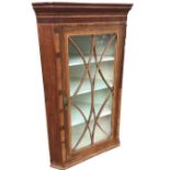 An early 19th century mahogany hanging corner cupboard, the moulded cornice above a crossbanded