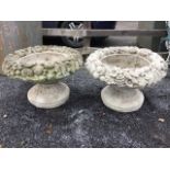 A pair of composition stone garden urns, the circular bowls cast with wide overflowing fruit and