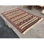 A North African flat weave carpet, the field with alternating stripes of cream and geometric motifs,