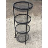 A three-tier wrought iron kitchen vegetable rack, with spiral twisted supports and circular wire