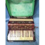 A boxed German accordian in red faux-marble case, with twenty keys, leather straps, etc. the
