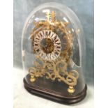 A Victorian brass skeleton timepiece on an ebonised oval base under a glass dome, the movement on
