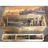 A rectangular tool box containing old tools including chisels, saws, augers, marking gauges, drill