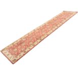 A contemporary oriental style wool runner woven with mottled red floral field framed by border of