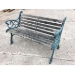 A cast iron garden bench with slatted back and seat framed by scrolled arms, supported on channelled