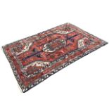 A Hamadan wool rug, the red field with geometric central medallion amidst scattered stylised