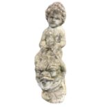 A composition stone garden font cast as a cherub riding a dolphin piped for water, raised on an