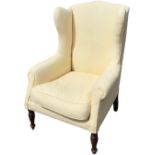 A Queen Anne style wing armchair with shaped padded back and roll-upholstered arms above a sprung