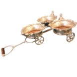 A silver plated table dinner wagon with three revolving cherub mounted coasters with foliate