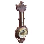 A Victorian carved oak barometer with leaf decoration, the circular aneroid instrument under