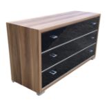 A contemporary faux walnut chest with three long glass fronted drawers mounted with shaped metal