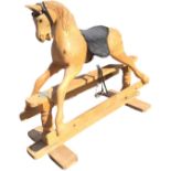 A carved pine rocking horse with glass eyes and leather harness, the saddle with leather straps &