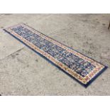 A Persian style runner, the dark blue field with scrolling foliage within a triple scrolled