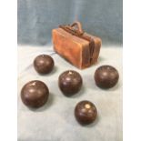A leather gladstone bag containing a set of lignum bowls with mother-of-pearl inlay, complete with a