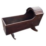 A Victorian pine cradle, the scalloped slatted arched hood over a flared rectangular body, on shaped