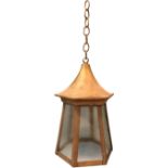 As Edwardian brass hall lantern with hexagonal tapering glass panels beneath a moulded canopy,