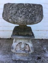 A composition stone garden urn cast with acanthus, on a square foot, raised on a shell and anthemion