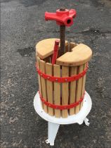 An unused home cider press, the enamelled cast iron handle on a central screw above a cylindrical