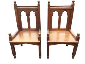 A pair of Victorian oak side chairs, the panelled backs with twin gothic carved apertures beneath