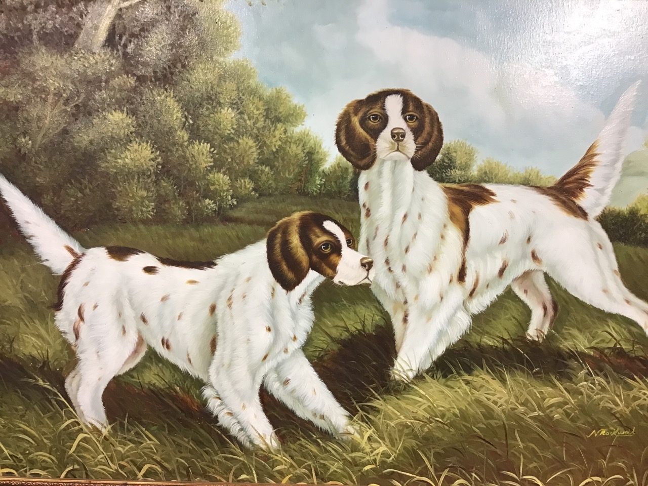 N Rockwell, oil on canvas a pair of spaniels in a grassy field by trees, in moulded gilt frame. (