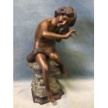 A 20th century bronze, seated fisher boy listening to the sea in a shell, with brown, black and