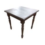 A square painted pine table, the chamfered top above a plain frieze, raised on tapering turned legs.