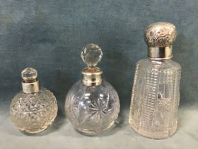 Three cut glass scent bottles with hallmarked silver collars, one London 1915, one with a repoussé