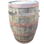 A large oak whiskey barrel, the staves bound by six riveted metal strap bands. (35in)