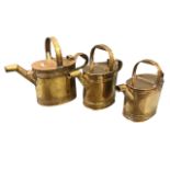 A graduated set of three Victorian brass watering cans, the rounded vessels with ribbed bands having