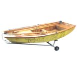 A 20ft sailing dingy, the painted mahogany ply boat complete with mast, oars, boom, etc., mounted on
