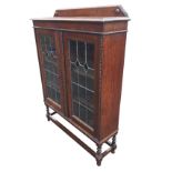 An Edwardian oak bookcase, the shaped moulded gallery and moulded top above leaded glazed doors,