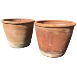 A large pair of terracotta plant pots of tapering form with moulded rims decorated with ribbed bands