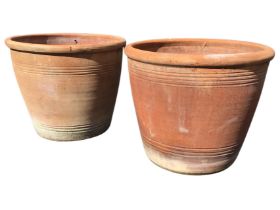 A large pair of terracotta plant pots of tapering form with moulded rims decorated with ribbed bands