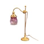 A brass Victorian style reading lamp, the mouth blown ribbed bud form cranberry glass shade on an