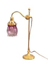 A brass Victorian style reading lamp, the mouth blown ribbed bud form cranberry glass shade on an