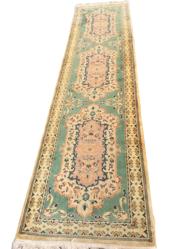 A Persian style wool runner, the green field with three floral medallions and scrolled foliate