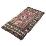 An antique Persian Yallameh rug fragment, the red ground with hooked medallion, within geometric and