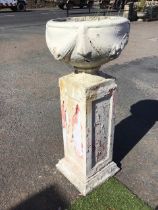 A white painted composition stone urn decorated with fabric and fruit swags, on a square base,