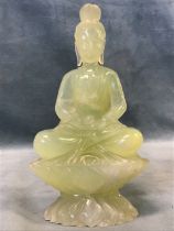 A Chinese carved pale green jade figure of a bodhisattva seated on a lotus base. (7in)