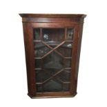 A late Victorian mahogany corner cabinet, with moulded cornice above an astragal glazed door