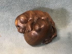 A Japanese hardwood netsuke of a pair of frolicking puppies with inset eyes and inlaid mother-of-