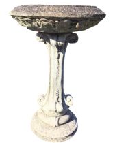 A composition stone circular leaf moulded birdbath on a scrolling plinth. (17.5in x 17.5in x 28in)