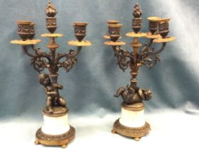 A pair of bronze candelabra, each with five urn shaped swagged candleholders on foliate scrolled