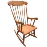 A beech rocking chair, the shaped crest rail above a spindle back, the seat on turned legs with