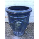 A large blue glazed terracotta planter, decorated with laurel swags and fleur-de-lys roundels, on