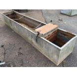 A rectangular galvanised trough with tubular rim, fitted with water supply box. (97.5in x 19in x