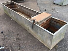 A rectangular galvanised trough with tubular rim, fitted with water supply box. (97.5in x 19in x