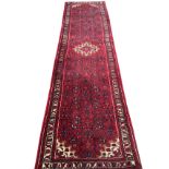 A Hoseinabad style Persian runner, the red ground with stylised geometric allover scrolling with