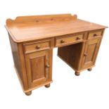 A Victorian style pine kneehole desk, the rectangular moulded top with upstand above three knobbed