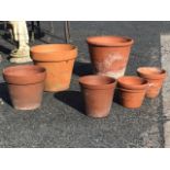 Six terracotta flowerpots, the largest hand thrown, another with impressed floral pattern to the